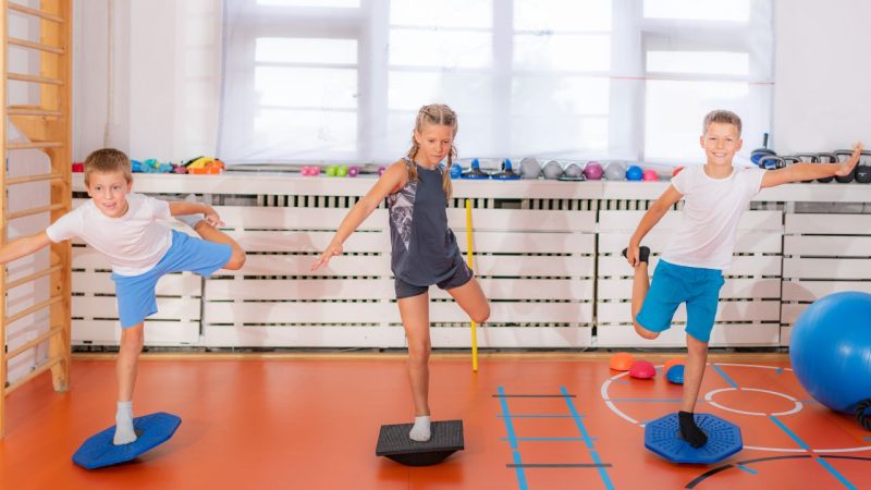 Zaburzenia integracji sensorycznej. Dzieci ćwiczące równowagę i koordynację na torze przeszkód, wspierające zmysł przedsionkowy.